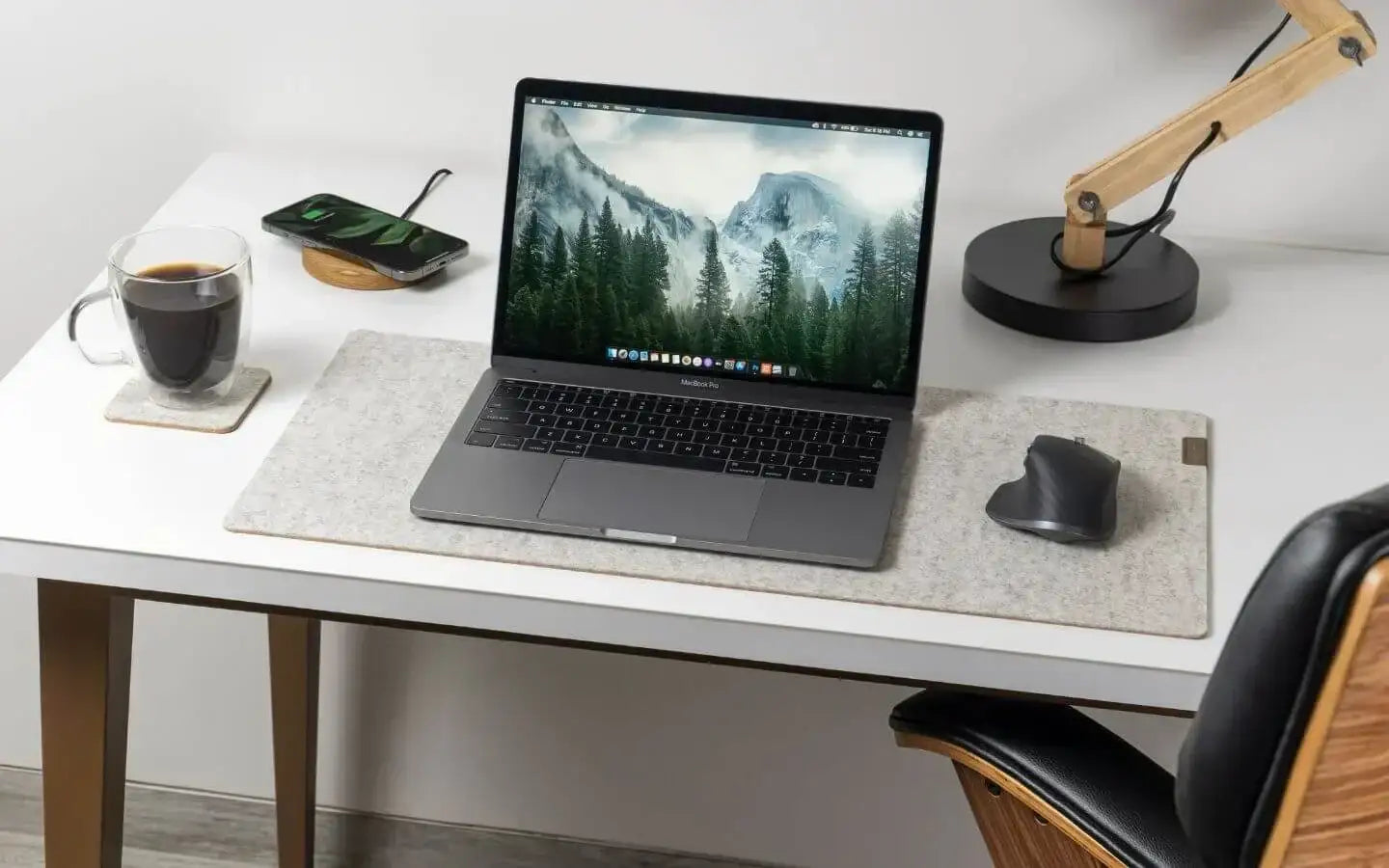 Minimalistyczne biurko z MacBookiem Pro, bezprzewodową myszką, lampką i kawą