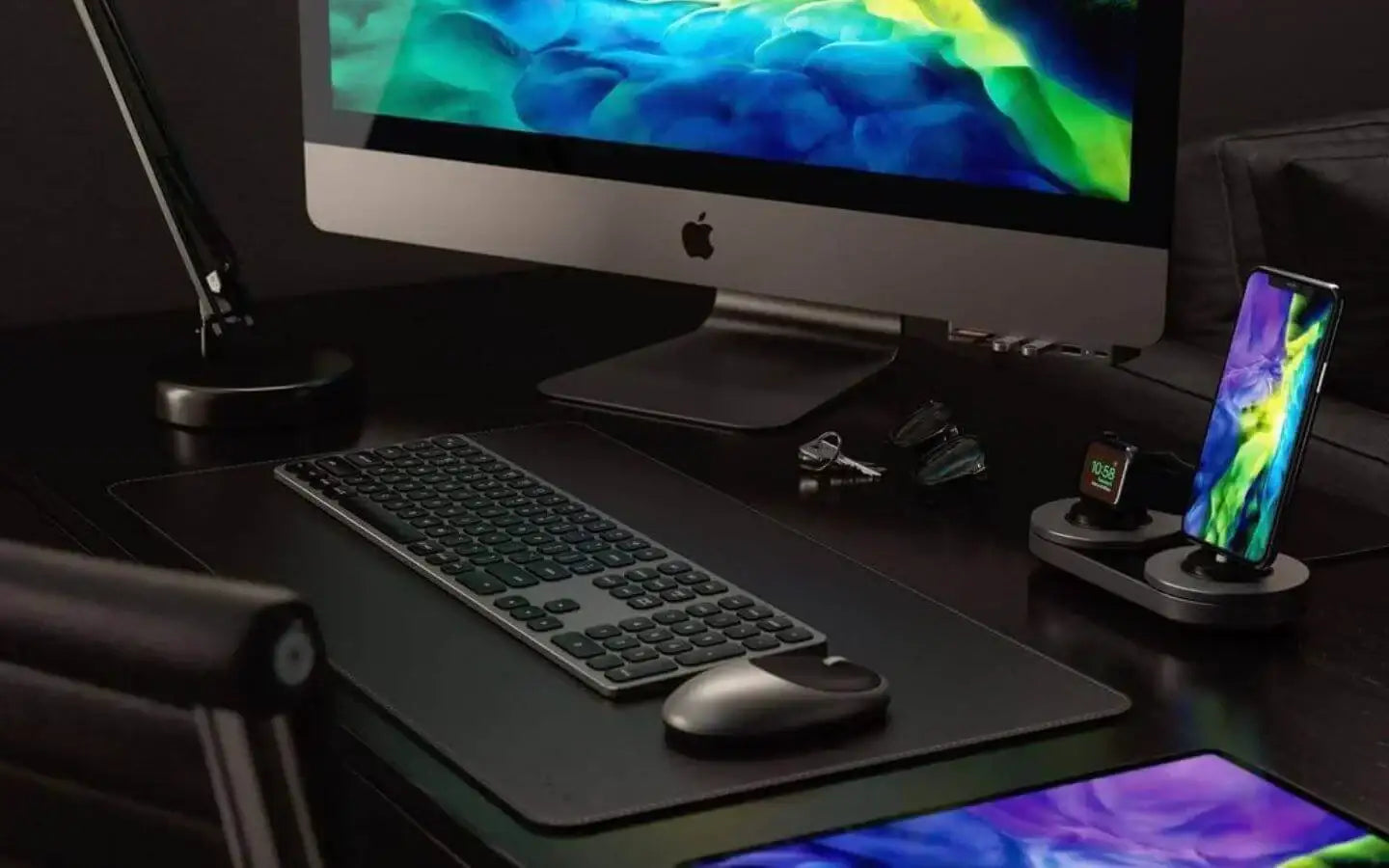 Nowoczesne stanowisko pracy z komputerem iMac, bezprzewodową klawiaturą, myszką, ładowarką do Apple Watch i smartfona na biurku