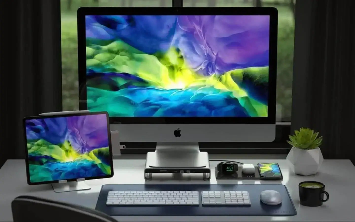 Biurko z komputerem Apple iMac, iPadem, smartwatchami, smartfonem, zieloną rośliną i kubkiem kawy