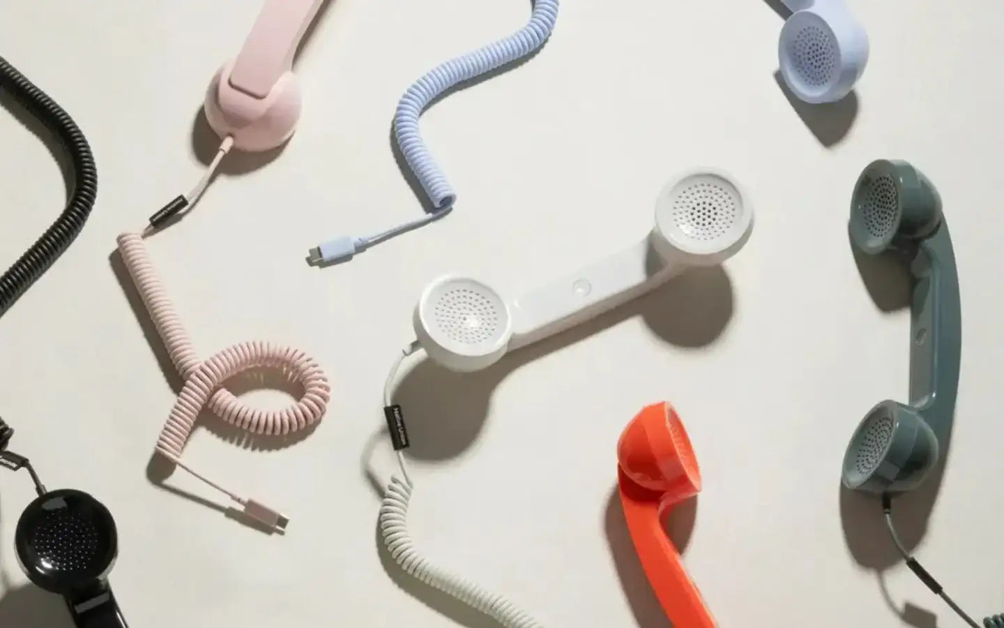 Kolorowe retro słuchawki telefoniczne z spiralnymi kablami na jasnym tle