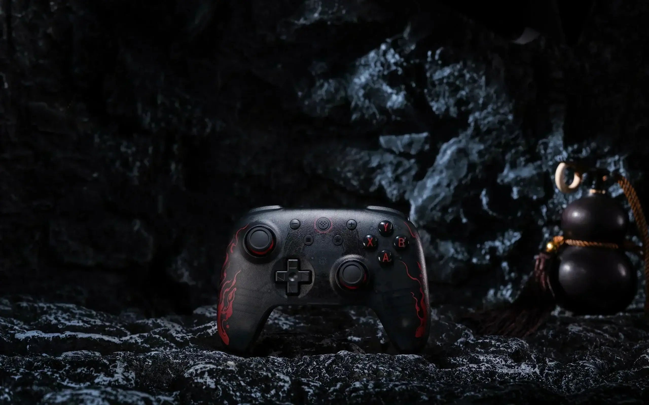 Czarny kontroler do gier z czerwonym wzorem na tle ciemnej skały, pad gamingowy