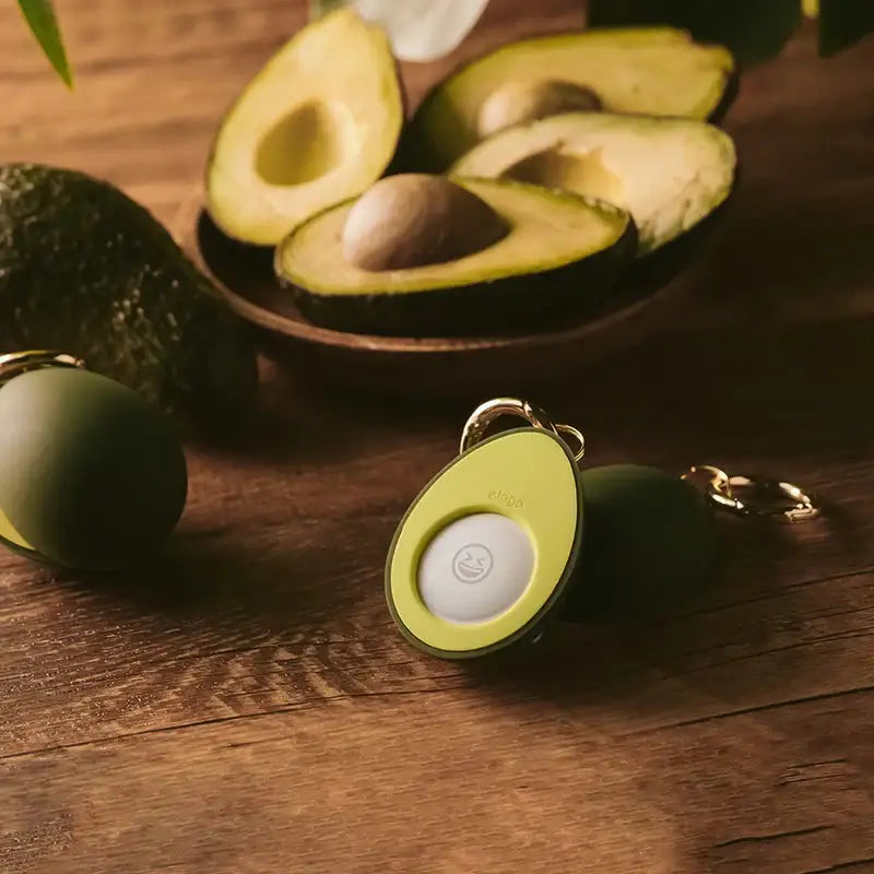 Zielone etui na AirPods w kształcie awokado z naturalnymi plasterkami awokado na drewnianym stole