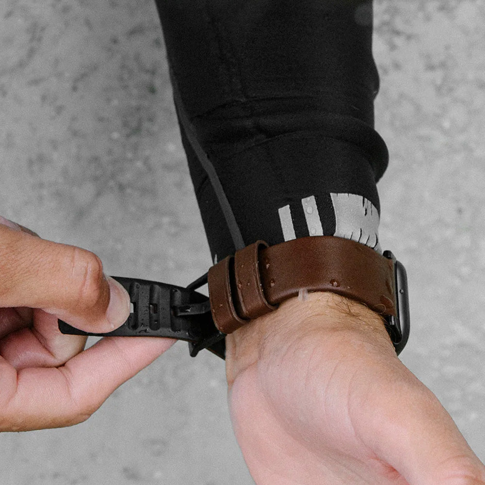 Brązowy pasek do Apple Watch na nadgarstku, zbliżenie na zapięcie, mokra skóra.