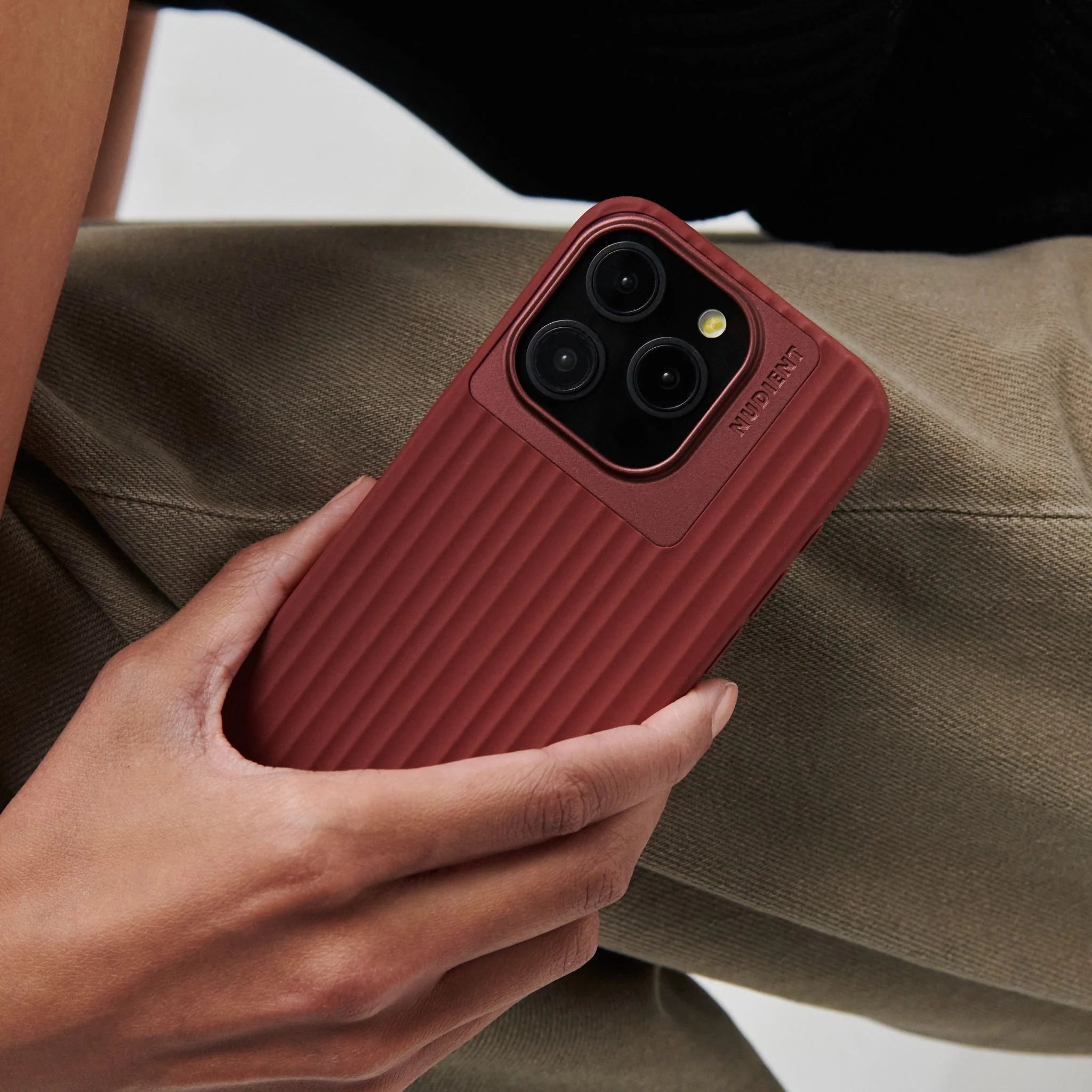 Etui na iPhone w kolorze bordowym z żebrowaną fakturą, trzymane w dłoni