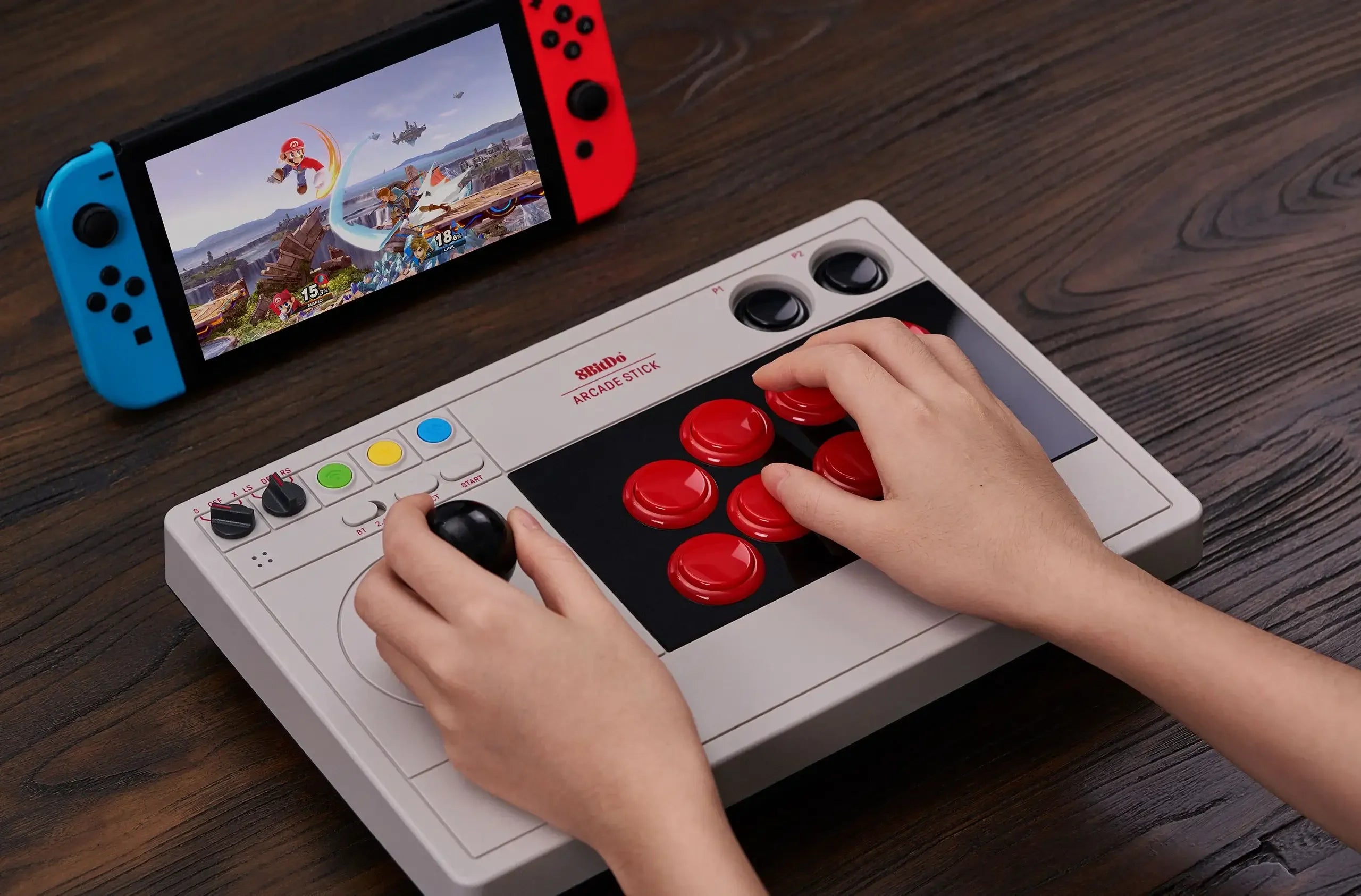 Joystick arcade i konsola Nintendo Switch podczas gry, kontroler z czerwonymi przyciskami na biurku