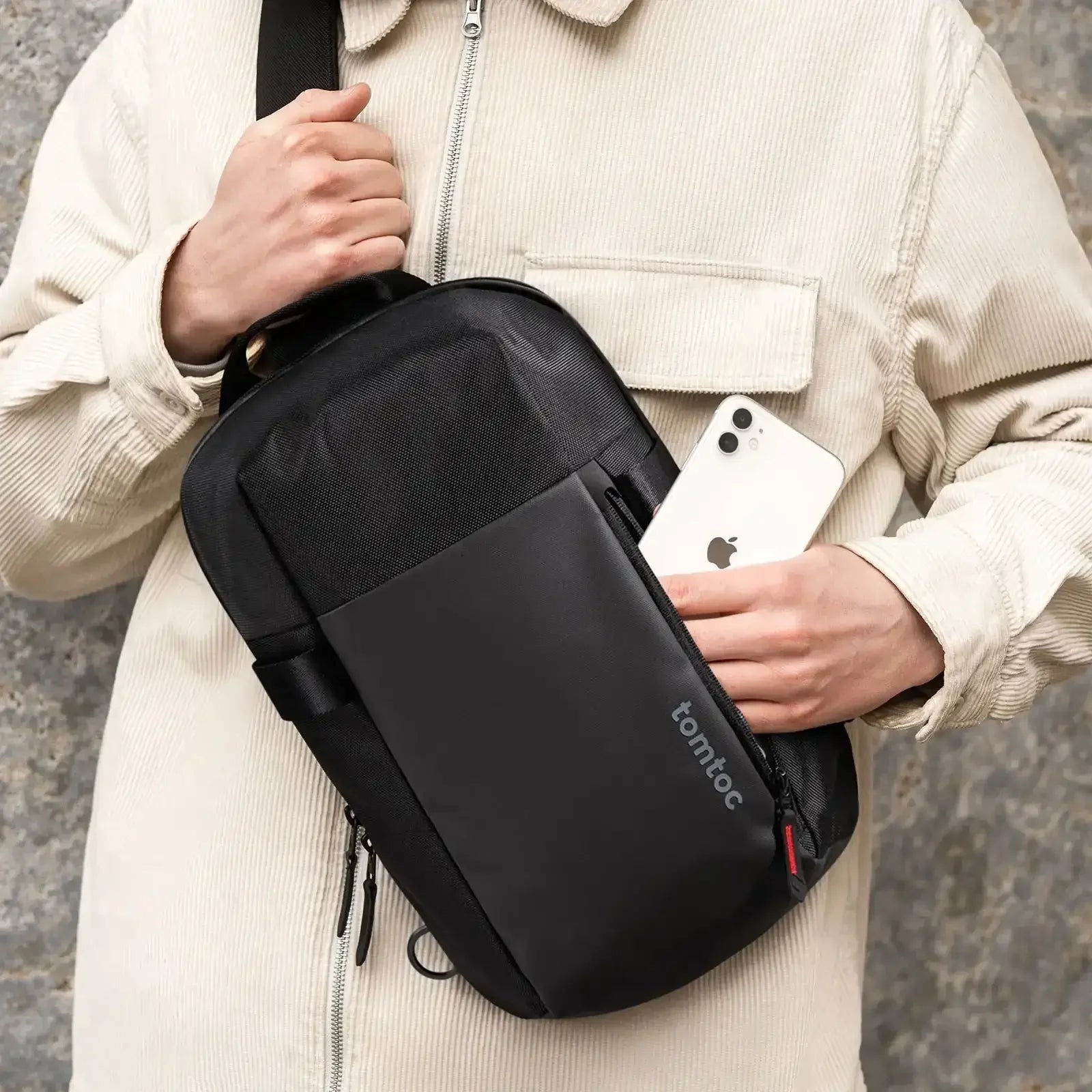 Czarna torba na ramię typu sling bag, kieszeń z suwakiem, smartfon, akcesoria biurowe