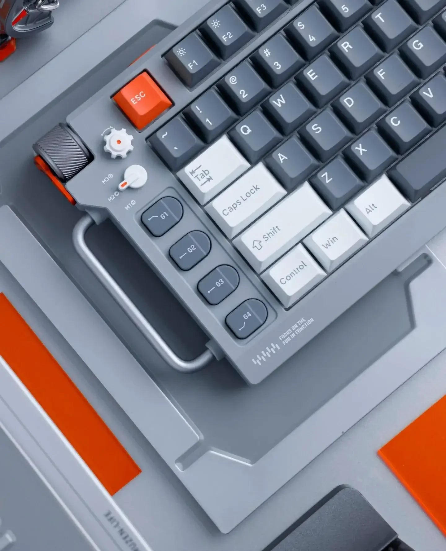 Klawiatura mechaniczna gamingowa z przyciskami makro, pokrętłem i szarymi keycapami, biurko.