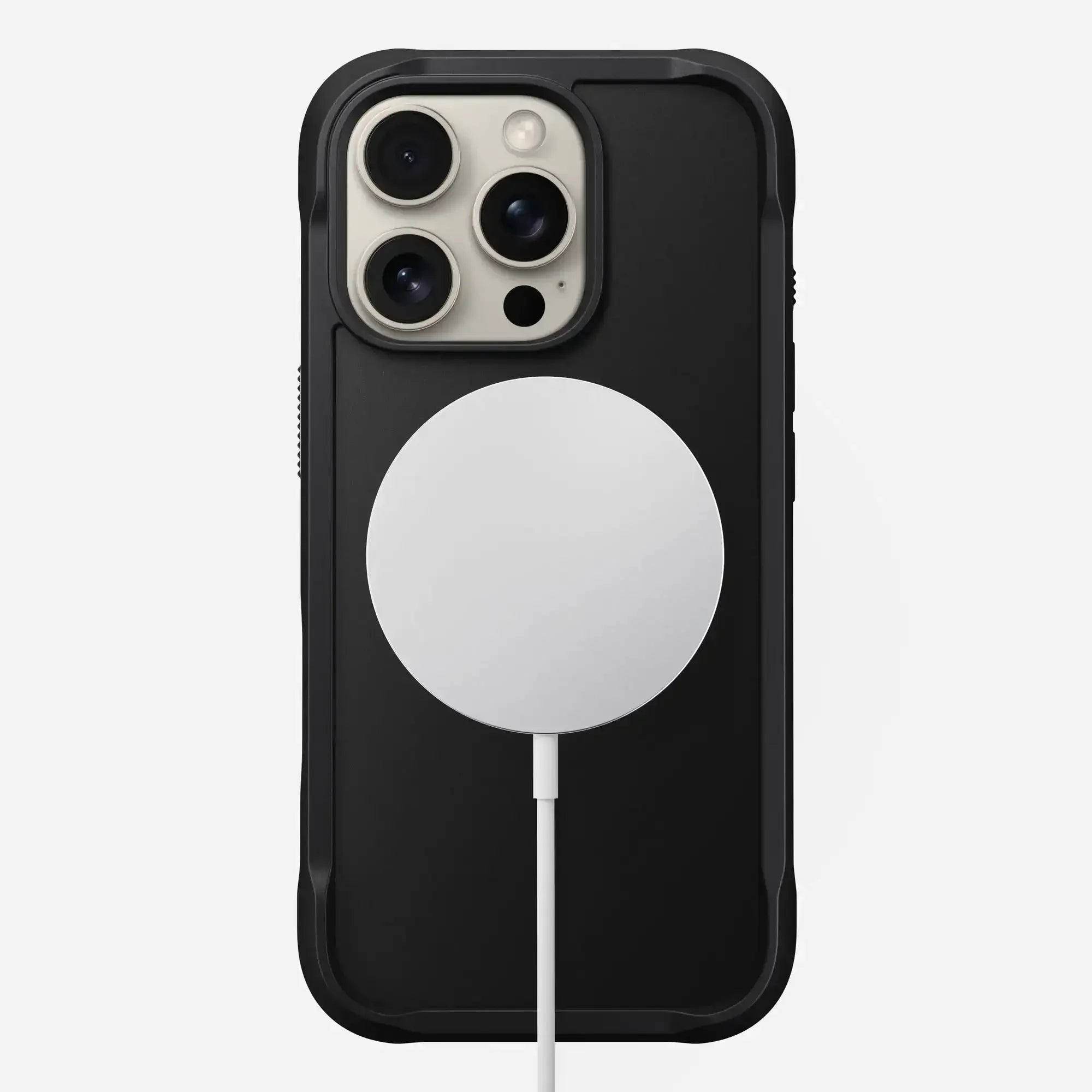 Czarny iPhone w etui z białą ładowarką MagSafe na białym tle, akcesoria do biura