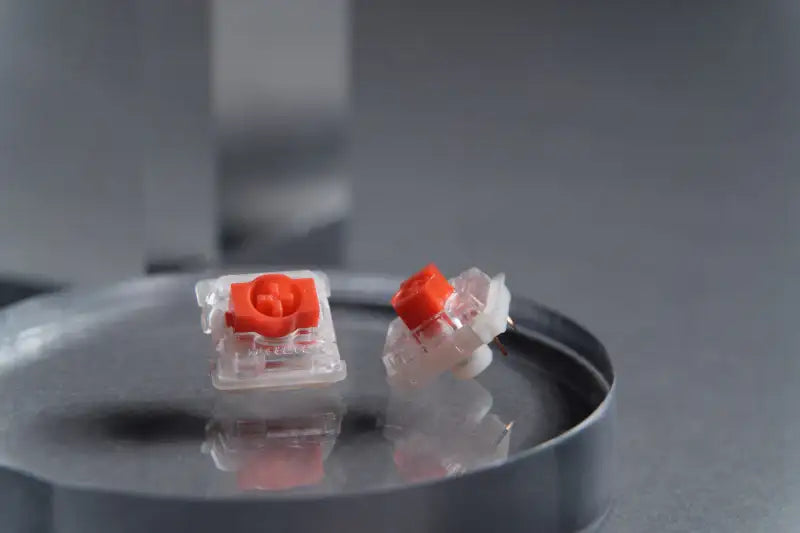 Przełączniki mechaniczne do klawiatury z czerwonym trzonem na szarym tle