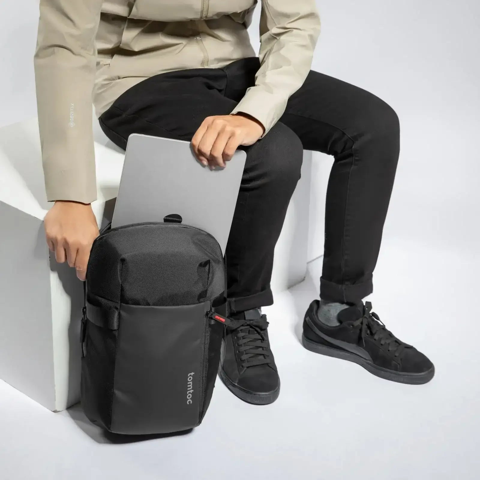 Osoba wkładająca laptopa do czarnego plecaka na biurowe akcesoria, wygodny setup do pracy