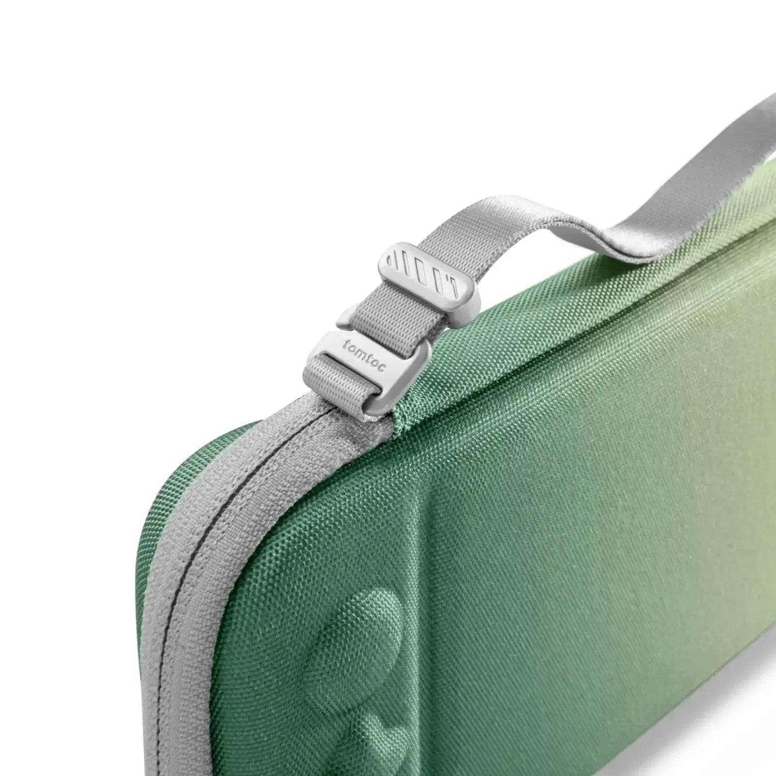 Detal zapięcia torby ochronnej na laptopa z zielonego materiału, szary pasek, akcesoria biurowe.