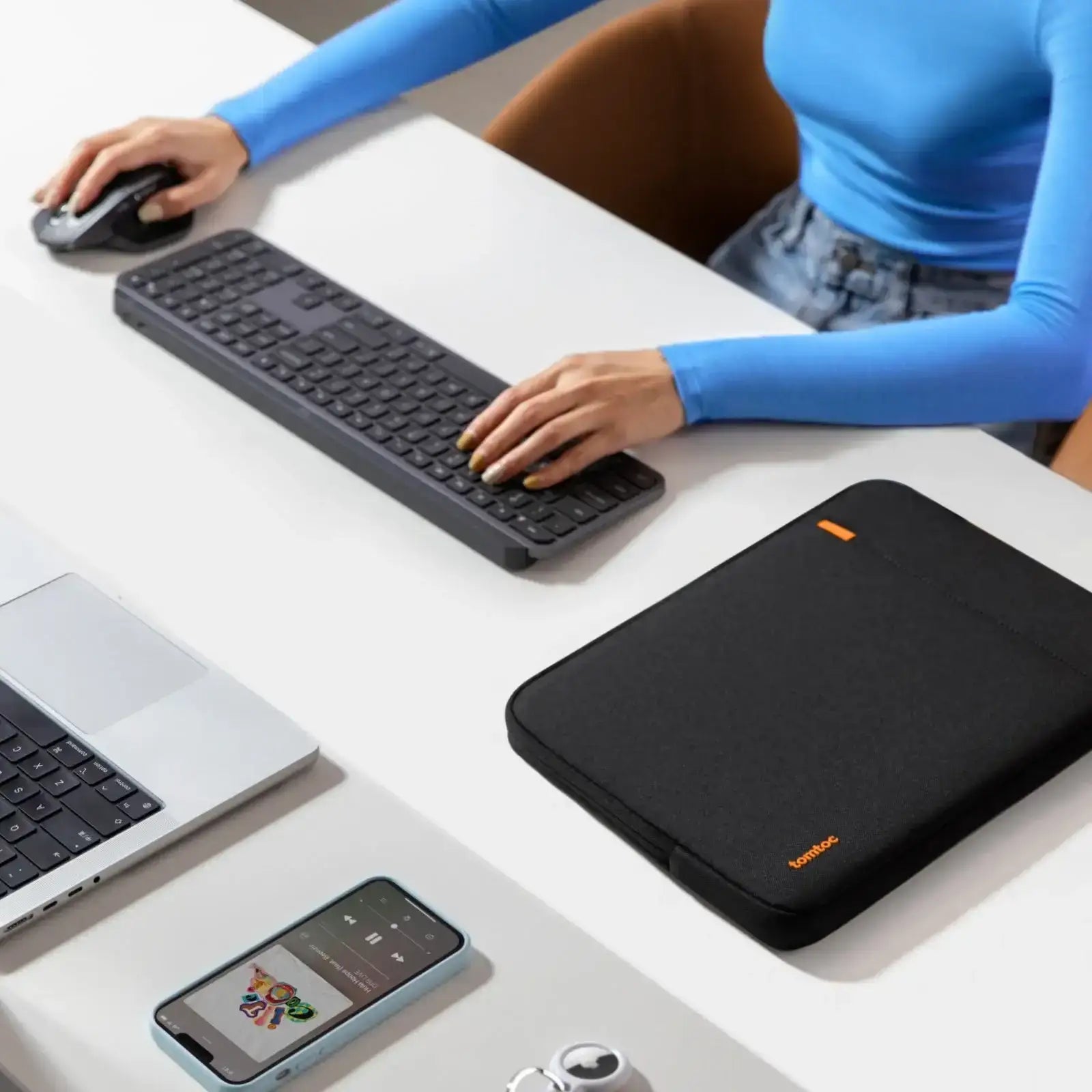 Nowoczesny desk setup z klawiaturą, myszką, etui na laptopa i smartfonem na biurku