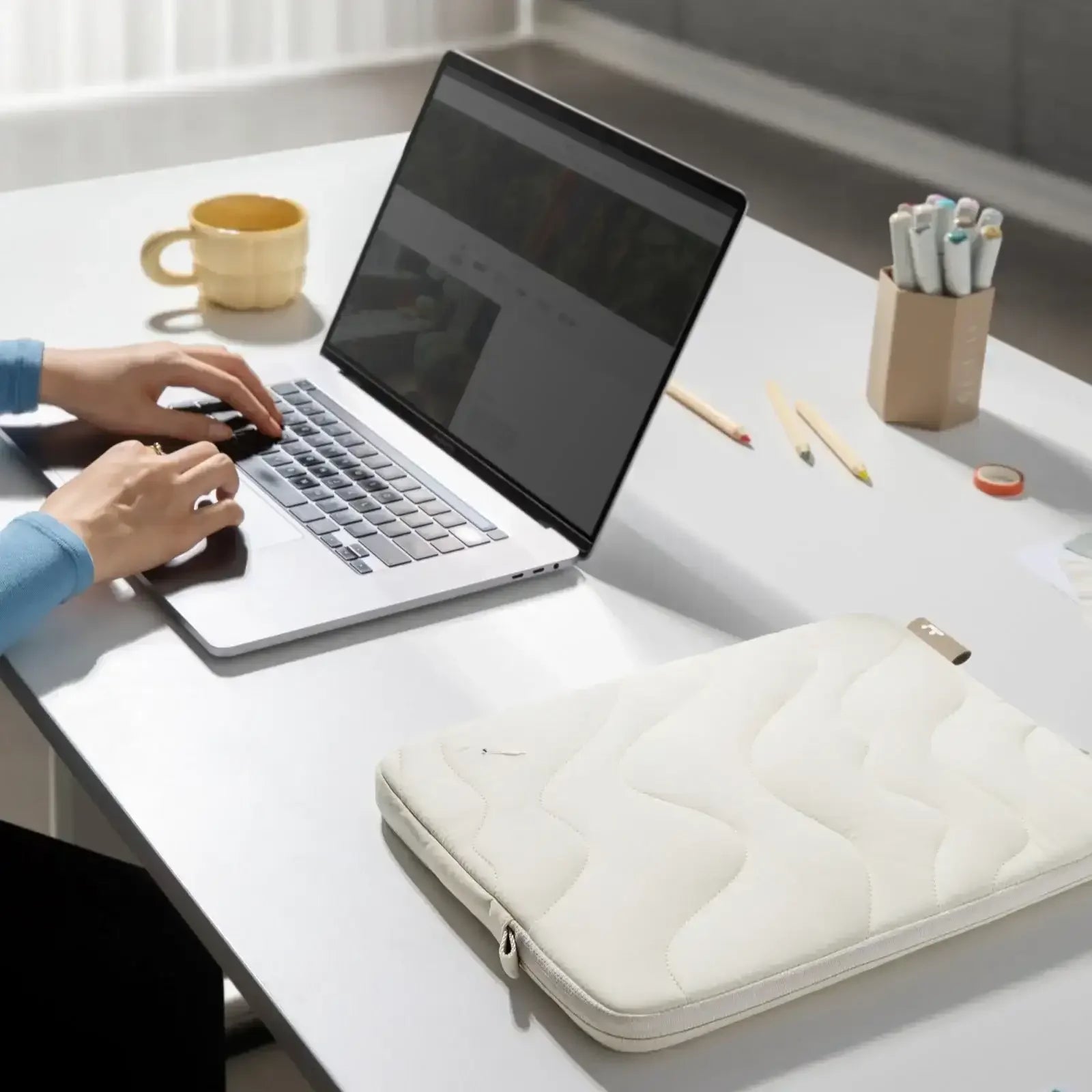 Praca przy laptopie na biurku, etui na laptopa, akcesoria do home office, nowoczesny setup biurowy