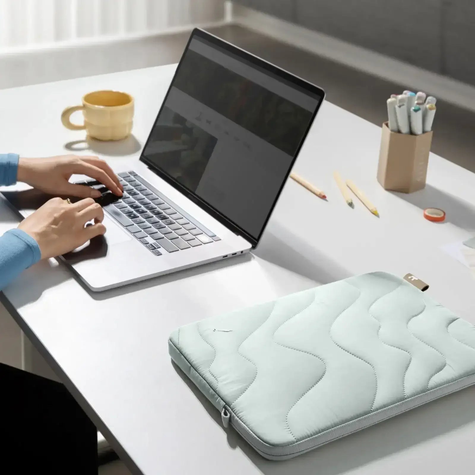 Nowoczesne biurko z laptopem, pokrowcem na laptopa i akcesoriami do pracy w home office.