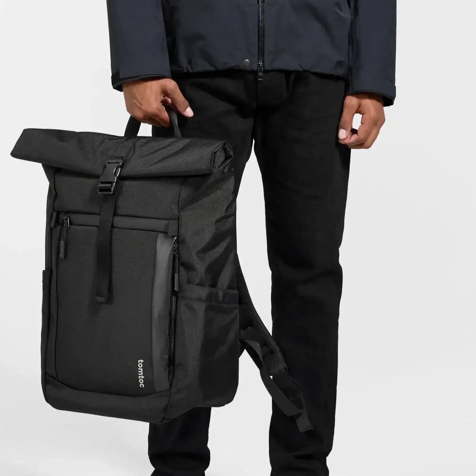 Czarny plecak rolltop tomtoc, męska ręka, minimalistyczny design, akcesoria do biura