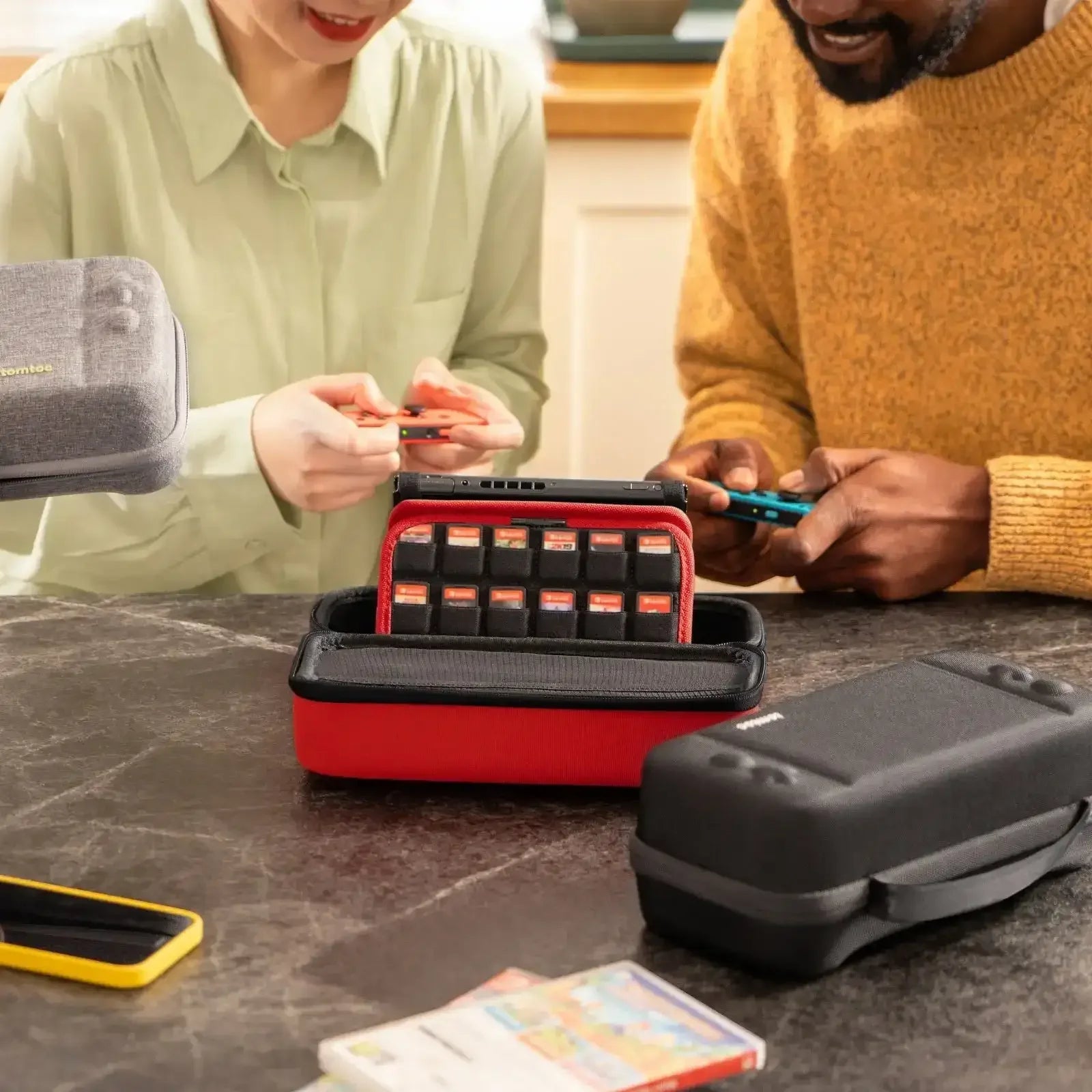 Etui na konsole Nintendo Switch z miejscem na gry, dwie osoby grają przy stole