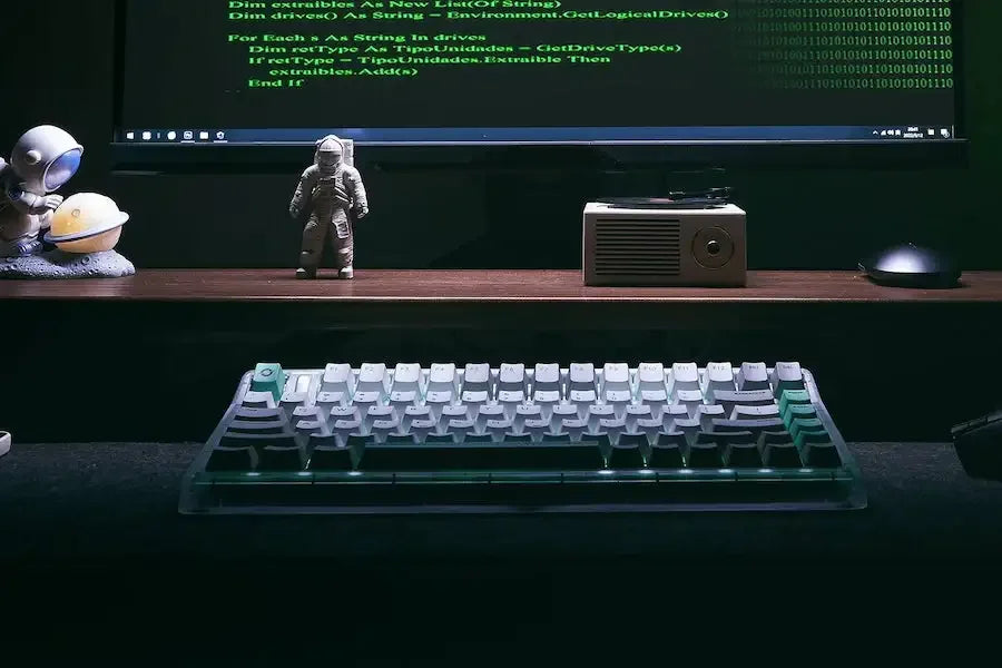 Klawiatura mechaniczna RGB na biurku, figurki astronautów, monitor z kodem