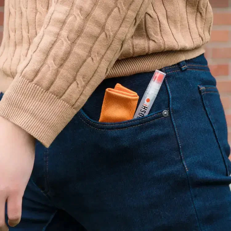 Poręczny flakon perfum i pomarańczowa ściereczka w kieszeni dżinsów, styl casual