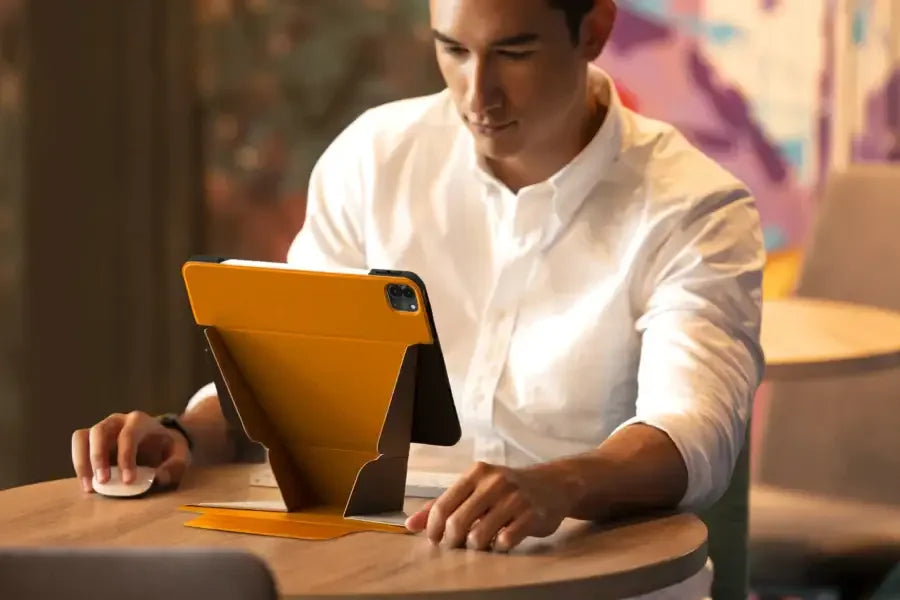 Mężczyzna pracujący przy stole, tablet w żółtym etui stojakowym, akcesoria biurowe