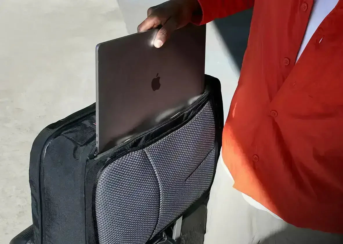 Osoba wkłada laptopa do czarnej torby na kółkach, idealnej do biura domowego