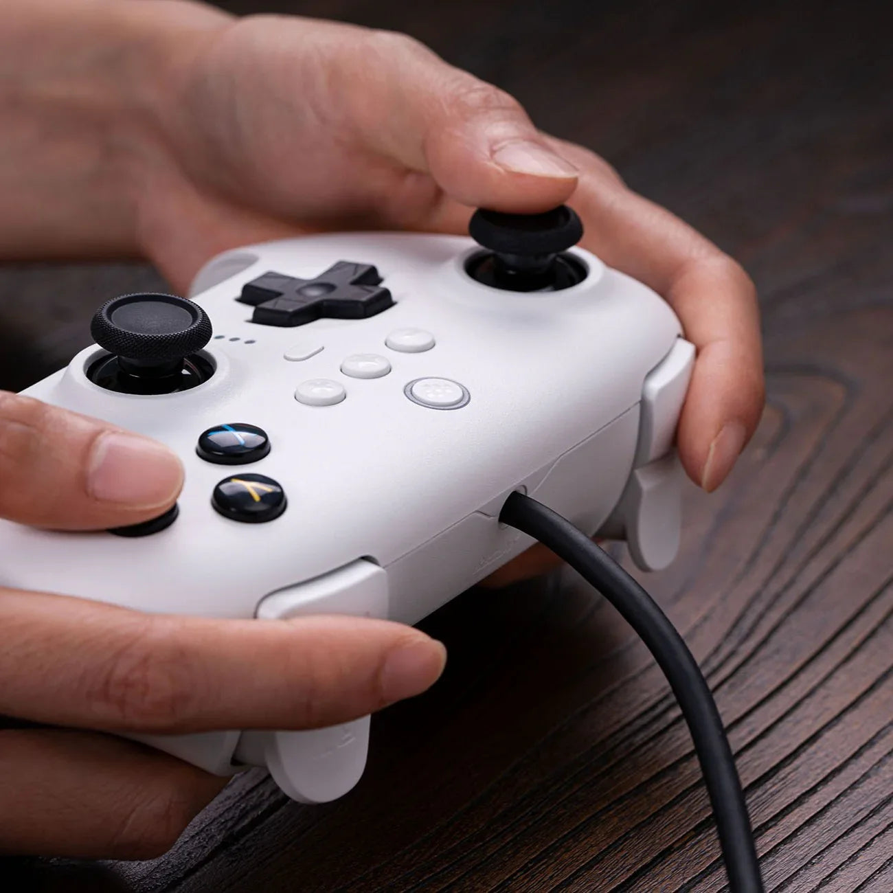 Biały kontroler gier z czarnymi joystickami w rękach, idealny do komfortowej gry w domu