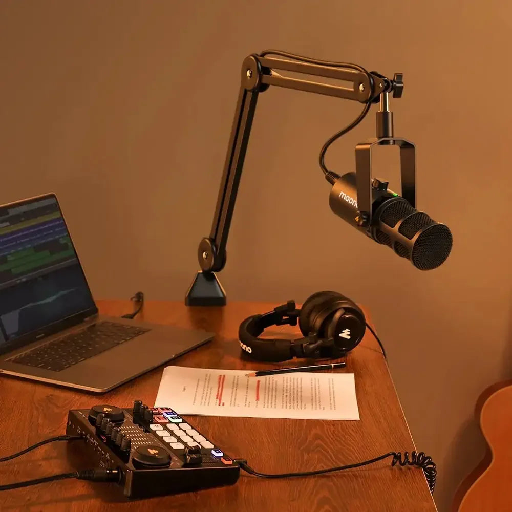 Biurko z laptopem, mikrofonem na ramieniu, słuchawkami i panelem audio do nagrywania podcastu