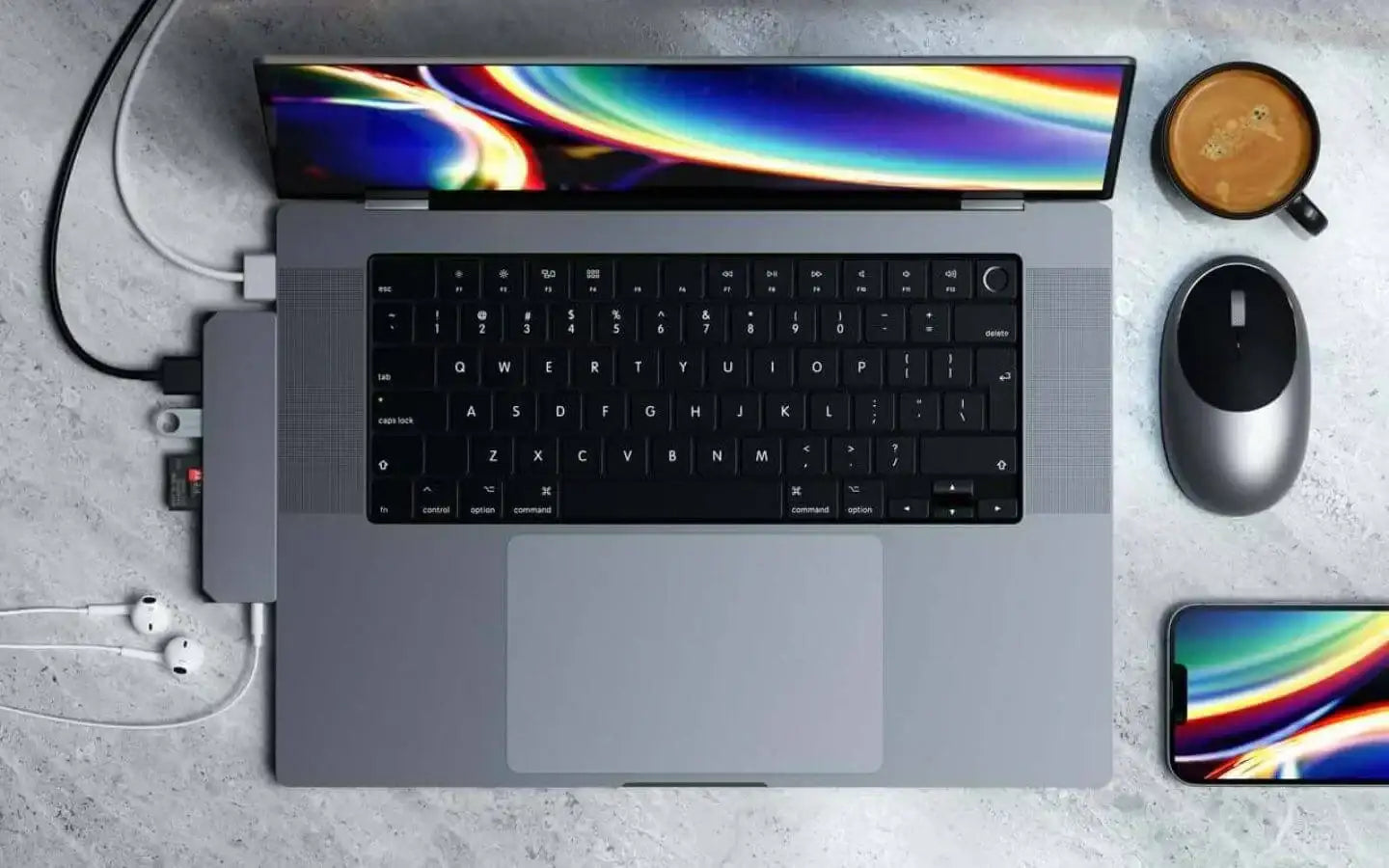 Laptop z podłączonymi akcesoriami: myszka, smartfon, słuchawki i filiżanka kawy na biurku