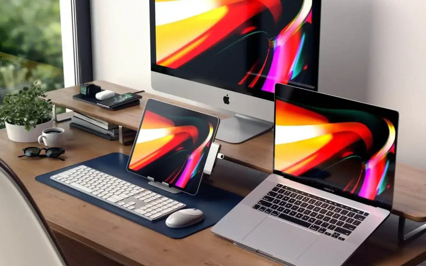 Nowoczesne biurko z komputerem iMac, laptopem MacBook, tabletem, klawiaturą, myszką i rośliną