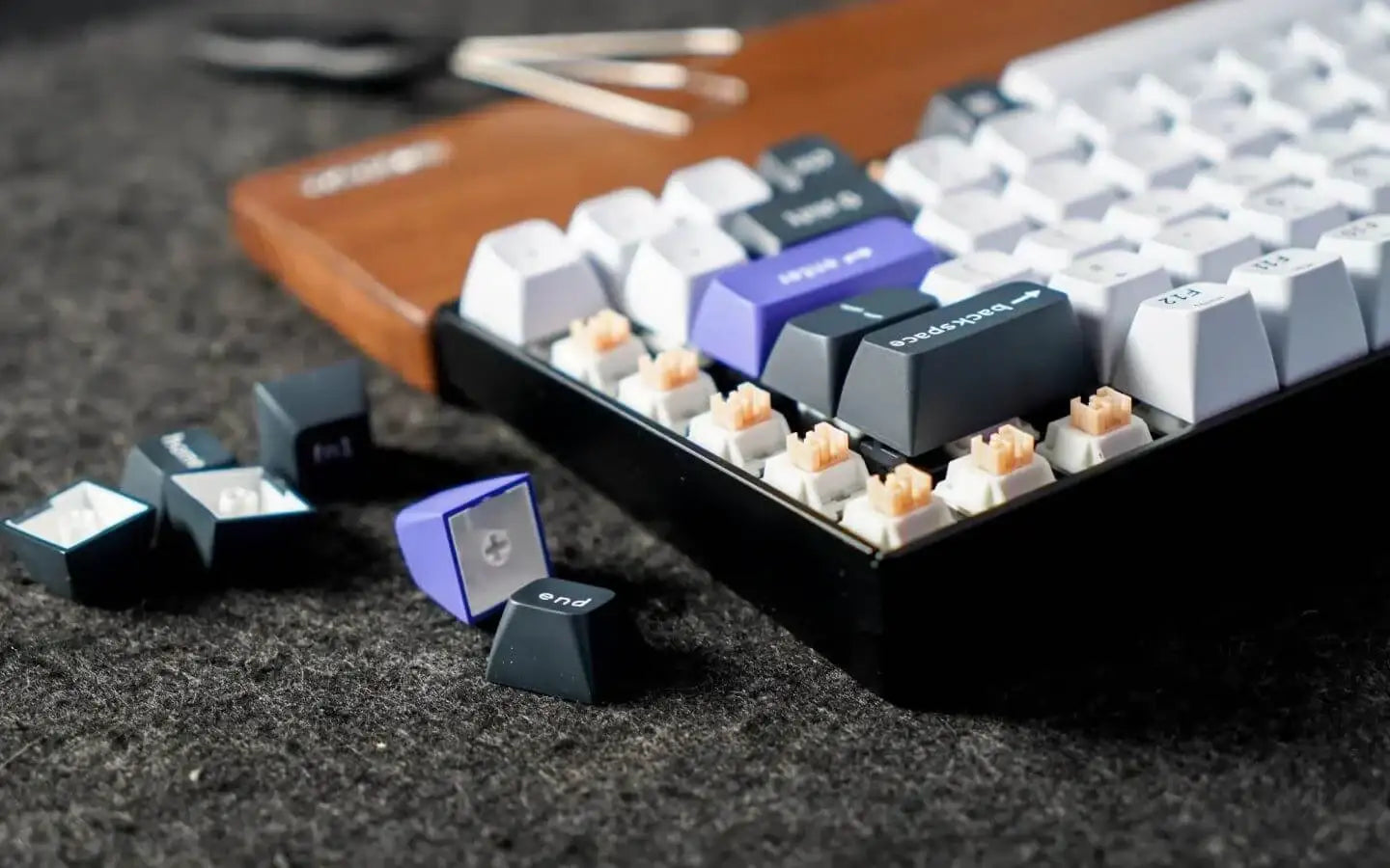 Mechaniczna klawiatura z wymienianymi klawiszami na czarno-białe i fioletowe na szarym tle