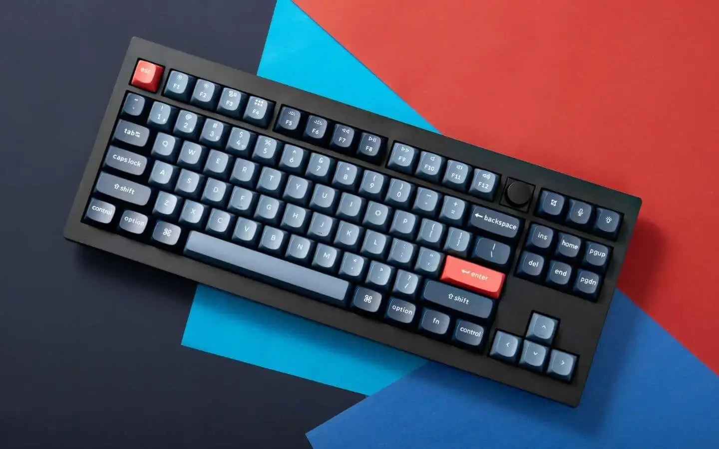 Czarna klawiatura mechaniczna z niebieskimi klawiszami i czerwonymi ESC oraz Enter na kolorowym tle