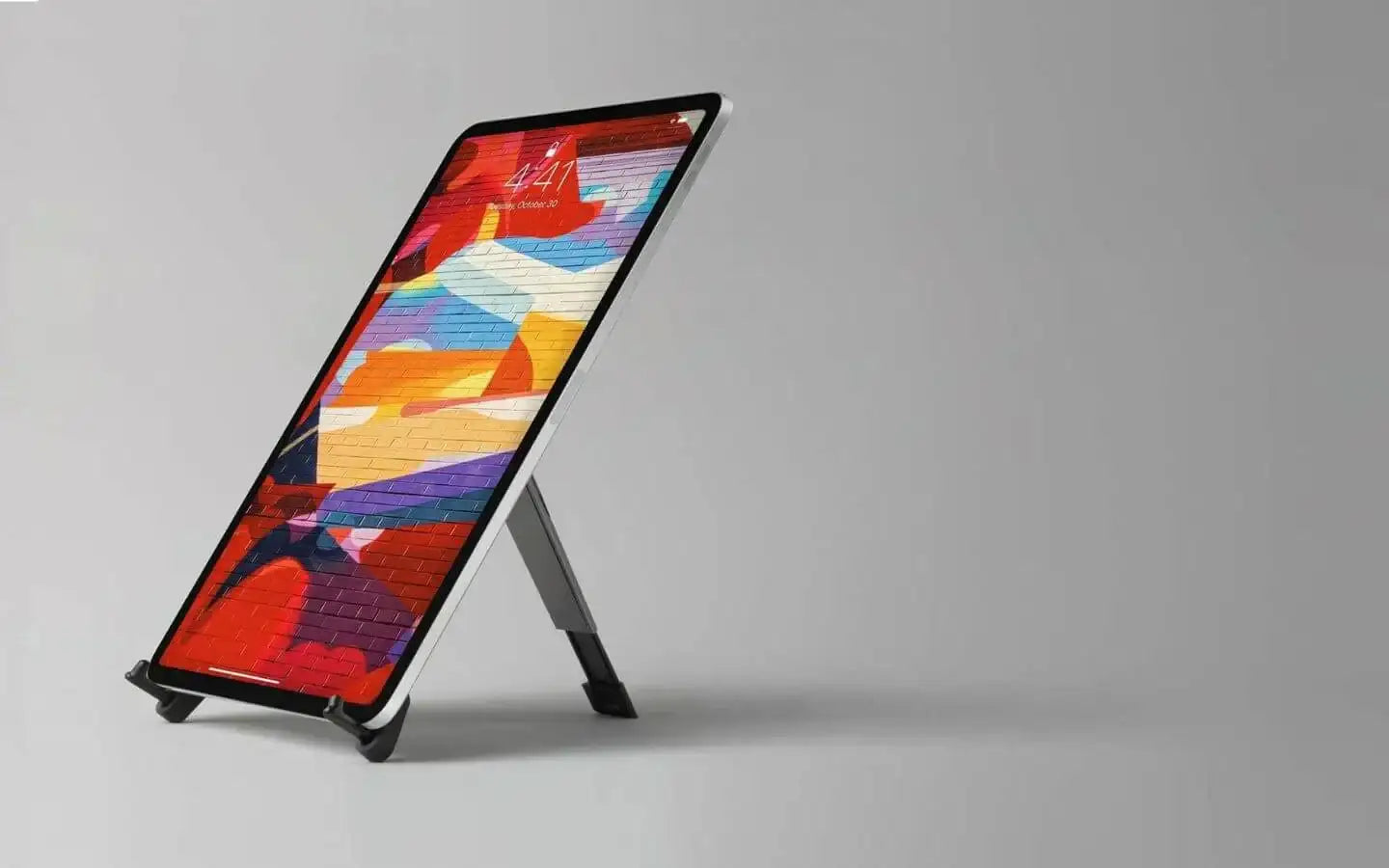 Tablet na stojaku ze stojakiem bocznym, kolorowy abstrakcyjny ekran, tło szare