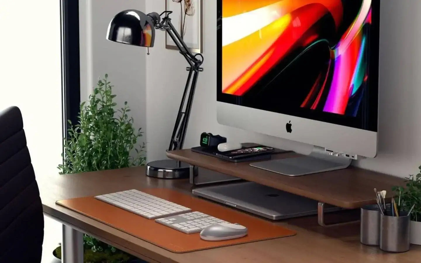 Biurko z komputerem Apple iMac, lampką, klawiaturą i roślinami w nowoczesnym miejscu pracy