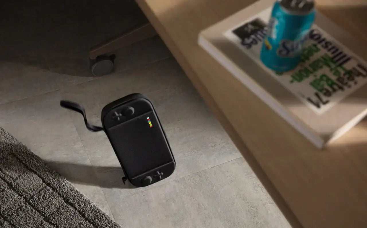 Czarna torba na konsolę gamingową na podłodze obok dywanu, puszka napoju na biurku