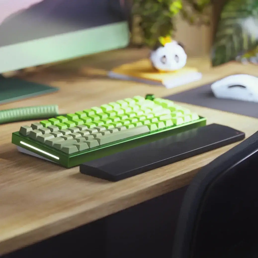 Zielona klawiatura mechaniczna na drewnianym biurku, nowoczesne stanowisko komputerowe.