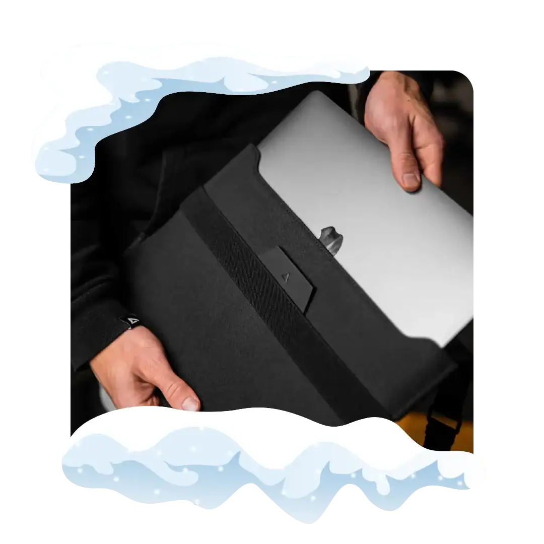 Czarna torba na laptopa z srebrnym MacBookiem, ręce trzymające sprzęt elektryczny