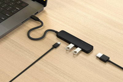 Czarny adapter USB-C z czterema portami podłączony do laptopa na drewnianym biurku