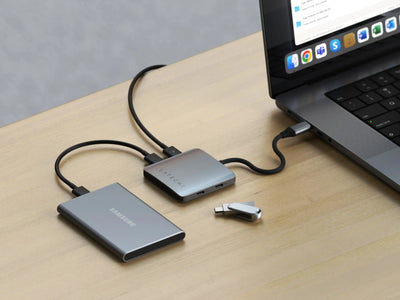 Hub USB-C z czterema portami i ładowaniem podłączony do laptopa na biurku, akcesoria biurowe