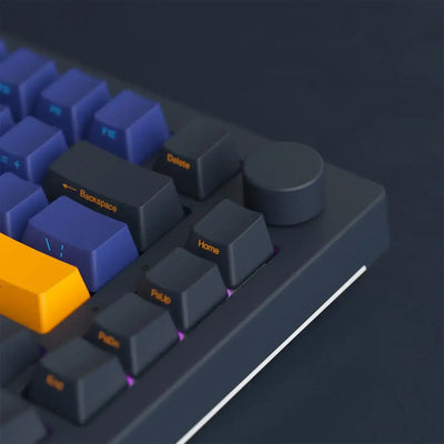 Ciemna klawiatura mechaniczna z pokrętłem, fioletowe i żółte keycapy, podświetlenie RGB.