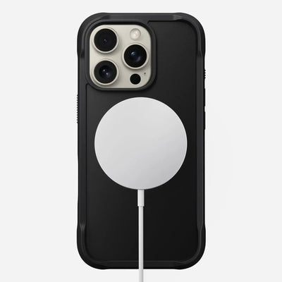 Czarny iPhone w etui z białą ładowarką MagSafe na białym tle, akcesoria do biura