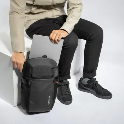 Osoba wkładająca laptopa do czarnego plecaka na biurowe akcesoria, wygodny setup do pracy