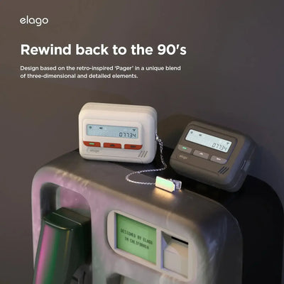 Dwie etui na AirPods stylizowane na pager retro, białe i czarne, leżące na automacie.