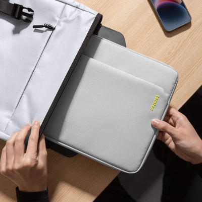 Szara torba na laptopa tomtoc na biurku, obok smartfon, akcesoria do home office