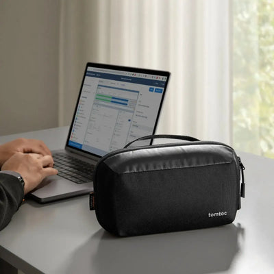 Czarna torba na akcesoria biurowe na biurku obok laptopa w nowoczesnym home office