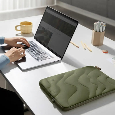 Minimalistyczne biurko z laptopem, zielonym etui na laptopa i organizerem na akcesoria biurowe