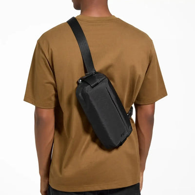 Czarna torba na ramię typu sling bag na plecach osoby w brązowej koszulce, akcesorium EDC