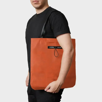 Składana torba tote bag w kolorze terakoty na ramieniu mężczyzny, minimalistyczny design