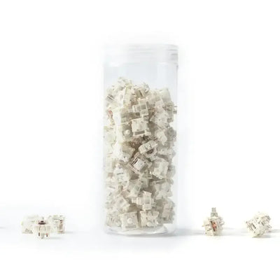 Zestaw białych switchy mechanicznych do klawiatury, w przezroczystym pojemniku.