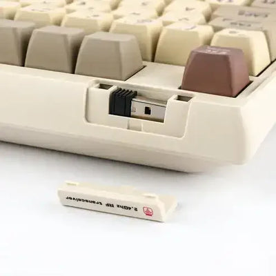 Zbliżenie na mechaniczna klawiaturę z adapterem Bluetooth w specjalnym schowku, keycapy retro.