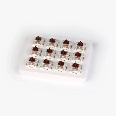 brązowe switche mechaniczne w przezroczystej obudowie na białej podstawce, akcesoria do klawiatur