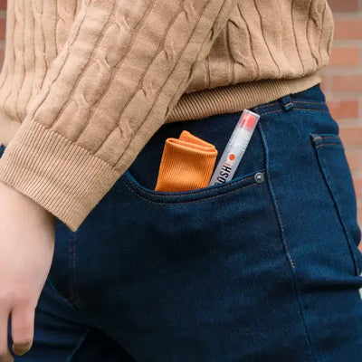Poręczny flakon perfum i pomarańczowa ściereczka w kieszeni dżinsów, styl casual